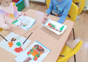 Dzieci wykonują jesienne drzewo odbijając pomalowaną część.