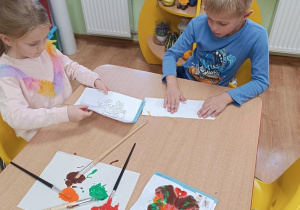 Dzieci wykonują jesienne drzewo odbijając pomalowaną część.