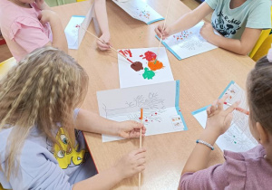 Dzieci wykonują jesienne drzewo odbijając pomalowaną część.