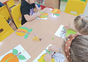 Dzieci wykonują jesienne drzewo odbijając pomalowaną część.