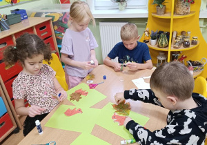 Dzieci wycinają wiewiórkę i doklejają jej ogon z liści.