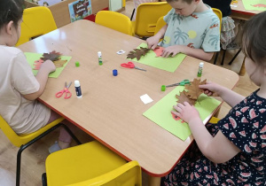 Dzieci wycinają wiewiórkę i doklejają jej ogon z liści.