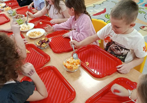 dzieci przygotowują owocowe szaszłyki