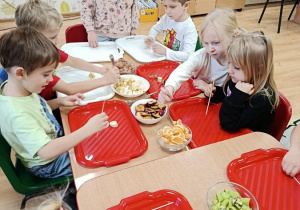 dzieci przygotowują owocowe szaszłyki