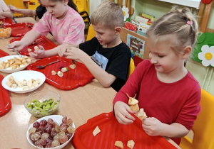 dzieci przygotowują owocowe szaszłyki