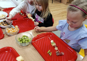 dzieci przygotowują owocowe szaszłyki