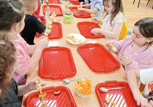 dzieci przygotowują owocowe szaszłyki