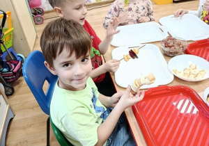 dzieci przygotowują owocowe szaszłyki