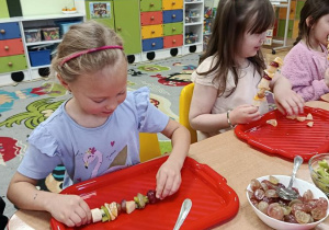 dzieci przygotowują owocowe szaszłyki