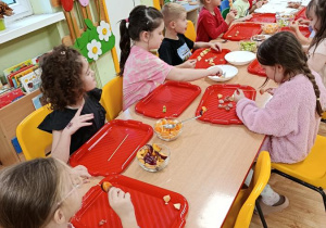 dzieci przygotowują owocowe szaszłyki