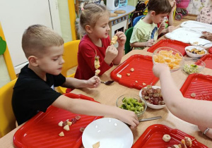 dzieci przygotowują owocowe szaszłyki