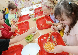 dzieci przygotowują owocowe szaszłyki