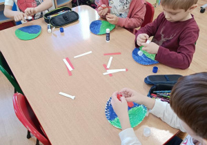 Dzieci sklejają białe i czerwone paski a następnie składają z nich flagę i rysują flamastrami z czym kojarzy się Ojczyzna.