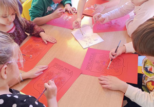 Dzieci malują pastą do zębów godło.