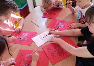 Dzieci malują pastą do zębów godło.