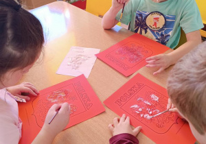 Dzieci malują pastą do zębów godło.