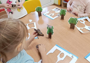 Dzieci wypychają elementy a następnie składają drzewo, rycerza na koniu, orła i gniazdo.