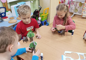 Dzieci wypychają elementy a następnie składają drzewo, rycerza na koniu, orła i gniazdo.