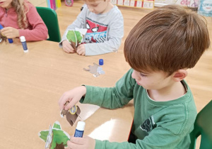 Dzieci wypychają elementy a następnie składają drzewo, rycerza na koniu, orła i gniazdo.