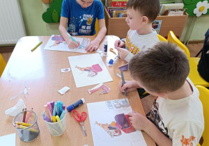 Dzieci wycinają, składają i sklejają lajkonika. W tle rysują rynek Krakowa.