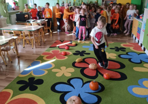 Dzieci pokonują slalom między dyniami.