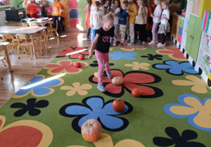 Dzieci pokonują slalom między dyniami.