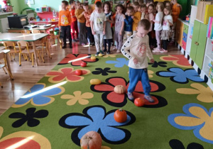 Dzieci pokonują slalom między dyniami.