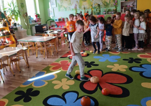 Dzieci pokonują slalom między dyniami.