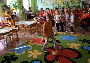 Dzieci pokonują slalom między dyniami.