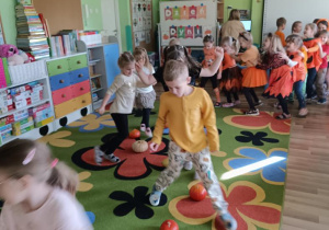 Dzieci pokonują slalom między dyniami.
