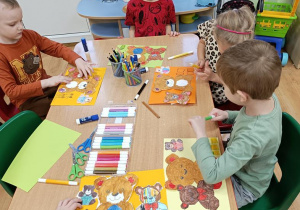 Dzieci naklejają misie wg. instrukcji nauczycielki.