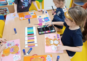 Dzieci naklejają misie wg. instrukcji nauczycielki.