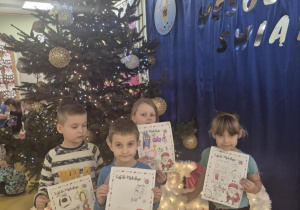 Dzieci z listami do Mikołaja przy choince.