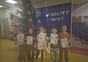 Dzieci z listami do Mikołaja przy choince.