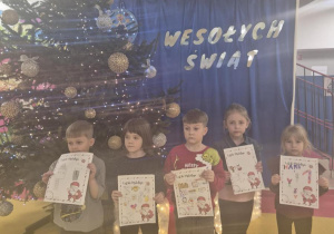 Dzieci z listami do Mikołaja przy choince.