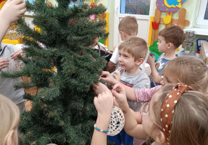 Dzieci ubierają choinkę.