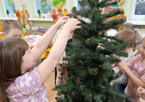 Dzieci ubierają choinkę.