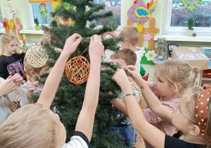 Dzieci ubierają choinkę.