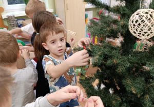 Dzieci ubierają choinkę.