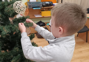 Dzieci ubierają choinkę.