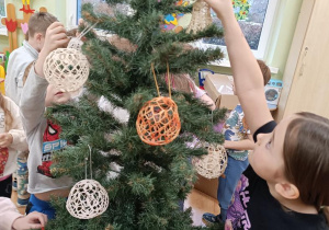 Dzieci ubierają choinkę.