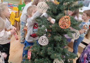 Dzieci ubierają choinkę.