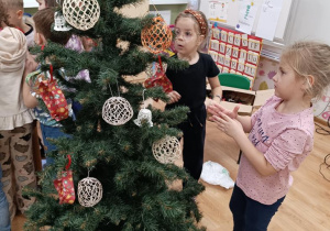 Dzieci ubierają choinkę.