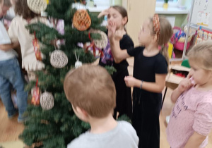 Dzieci ubierają choinkę.