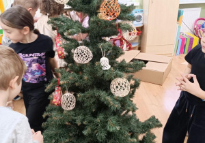 Dzieci ubierają choinkę.