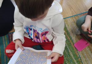 Dzieci oglądają karty przedstawiające złudzenia optyczne