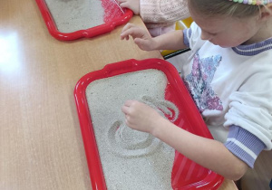 Dzieci podejmują próby pisania na piasku