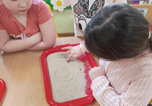 Dzieci podejmują próby pisania na piasku