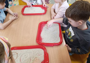 Dzieci podejmują próby pisania na piasku