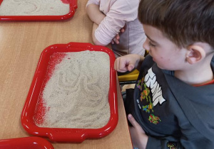 Dzieci podejmują próby pisania na piasku